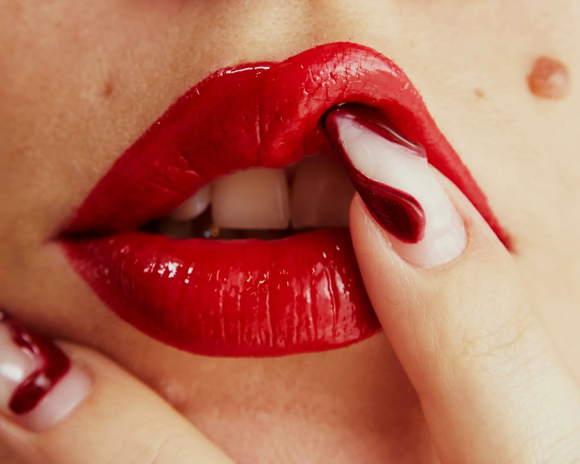 Ganz nahe Aufnahme roter Lippen mit einer Fingerkuppe dazwischen
