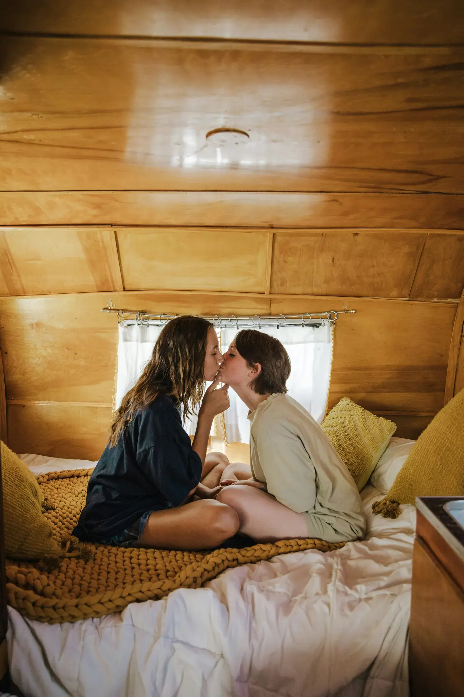 Zwei Frauen küssen sich im Bett eines Wohnwagens